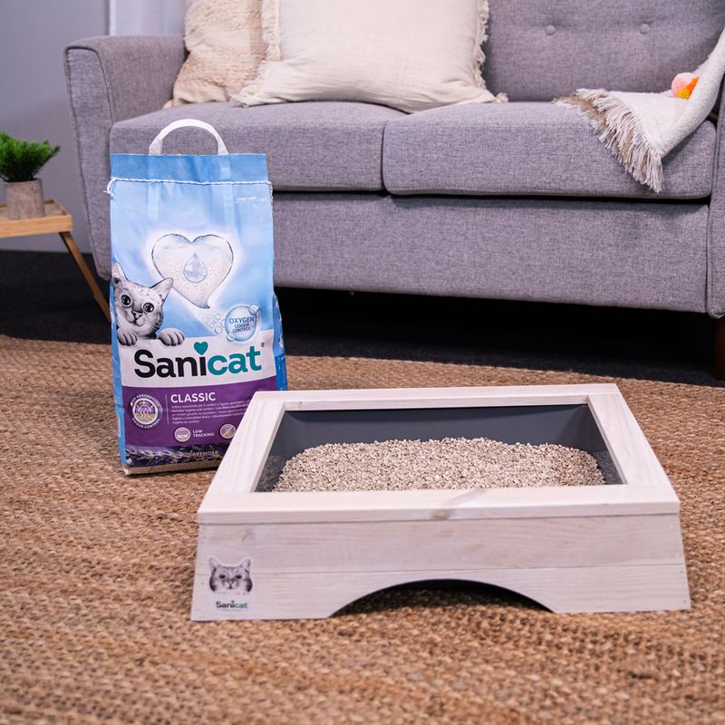 Sanicat Classic cat litter with oxygen freshness, packaging next to a filled wooden cat toilet on carpet.