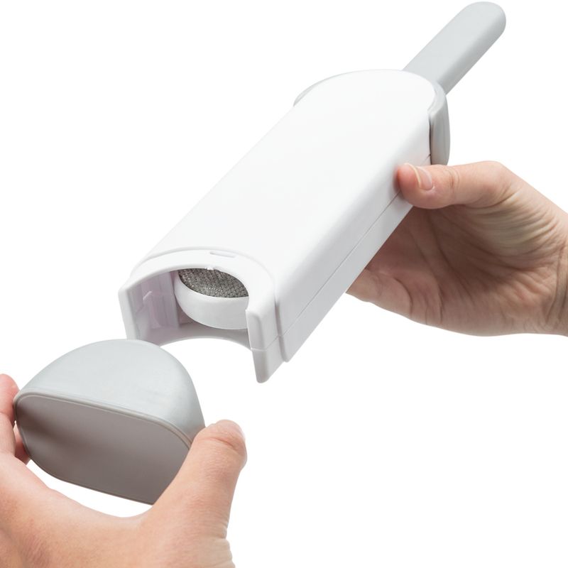 Hand showing the use of a white lint roller with removable container for cleaning.