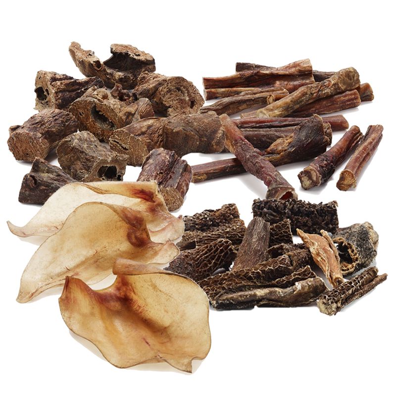Assorted natural dried animal chews including ears, tripe pieces, and sticks displayed together for product variety comparison.