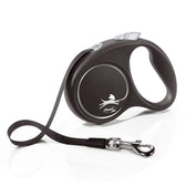 Flexi dog lead in black with ergonomic handle, silver logo and adjustable strap. Metal carabiner for attachment visible.