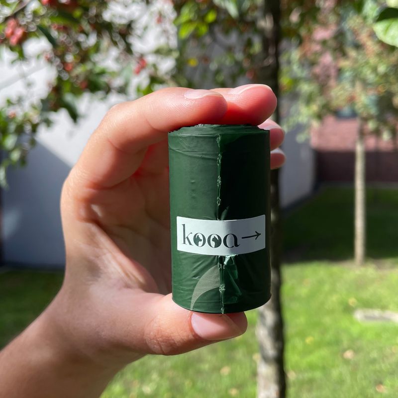 kooa. Dark green roll held in one hand, with kooa logo and arrow on it.
