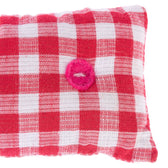 Red and white chequered cushion with a pink felt ring in the centre. Visible fabric texture.