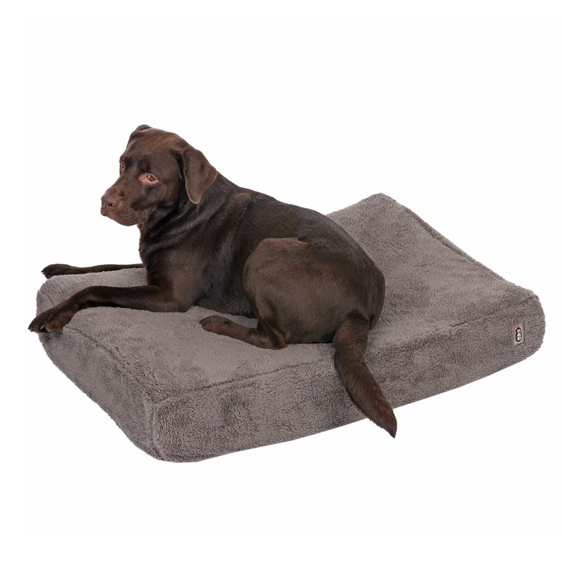 Brown dog lying on a grey, fluffy rectangular pet bed with visible brand logo on the side.
