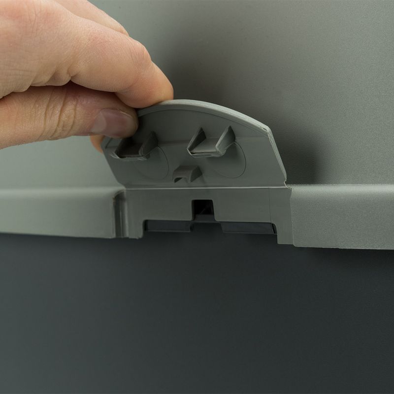 Hand opening a grey locking mechanism on a container. Close-up view of the clip for secure locking.
