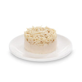 Close-up of a round piece of chicken meat on a white plate, finely shredded and ready to serve.