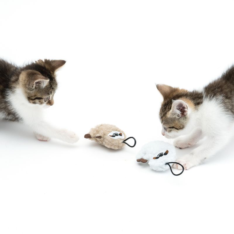 Two kittens playing with two plush toys shaped like mice, beige and white, with loops. Suitable for interactive play.