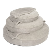 Three grey, round pet beds made of soft cord and plush material, stacked in different sizes.