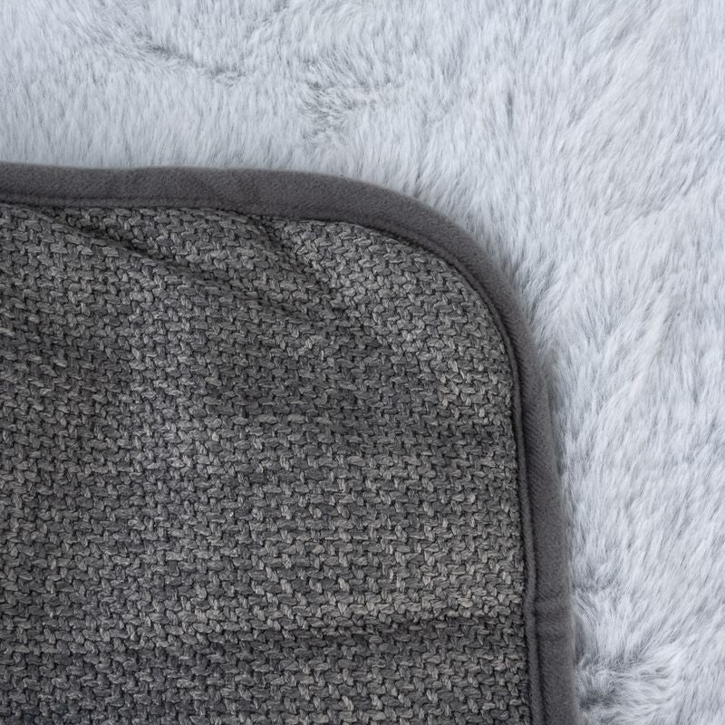 Close-up of a grey, textured mat with rounded edges on a fluffy white background.