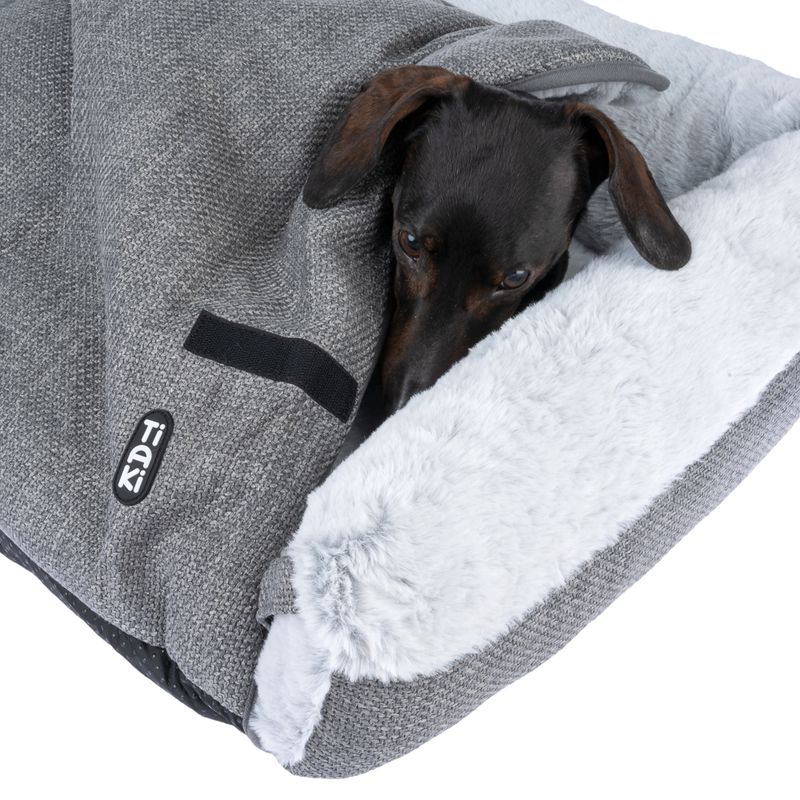 Tiaki dog blanket in grey with soft white plush inner side. Dachshund partially under the blanket.