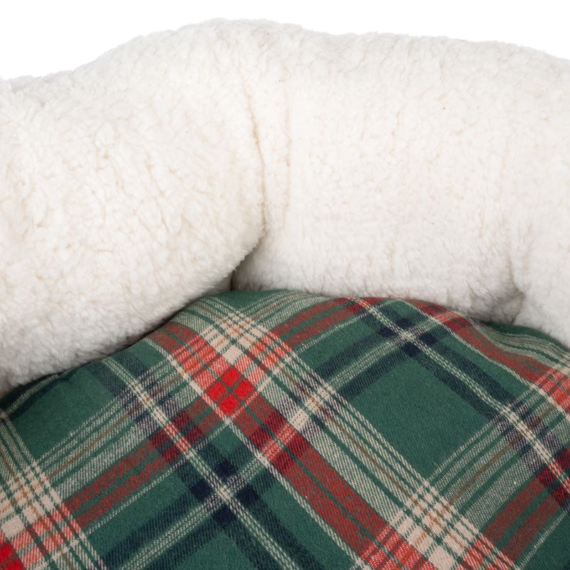 Close-up of a dog bed with a soft white plush border and a green-red check pattern on the lying surface.