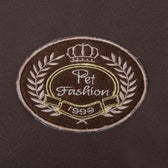 Pet Fashion 1999, embroidered emblem with crown and laurel wreath on brown fabric.