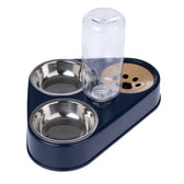 Dark blue food and water dispenser with two stainless steel bowls, transparent water bottle and beige paw pattern on the base.