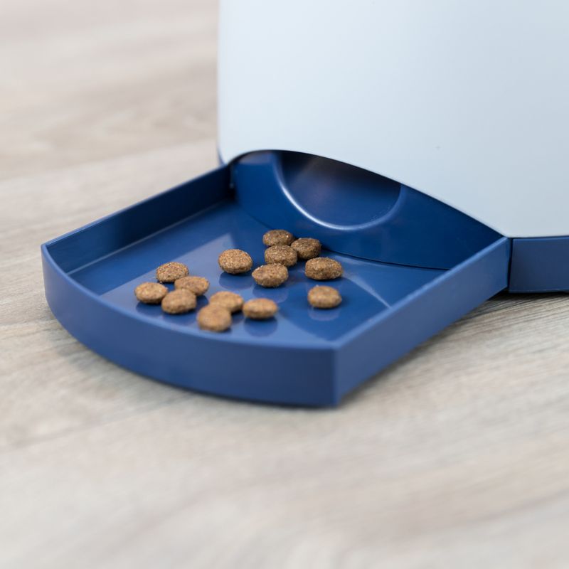 Automatic feeder with blue bowl, filled with brown dry food pieces.