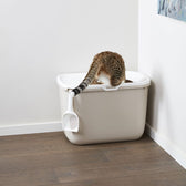 Cat toilet with white lid and integrated litter scoop, cat using the toilet.