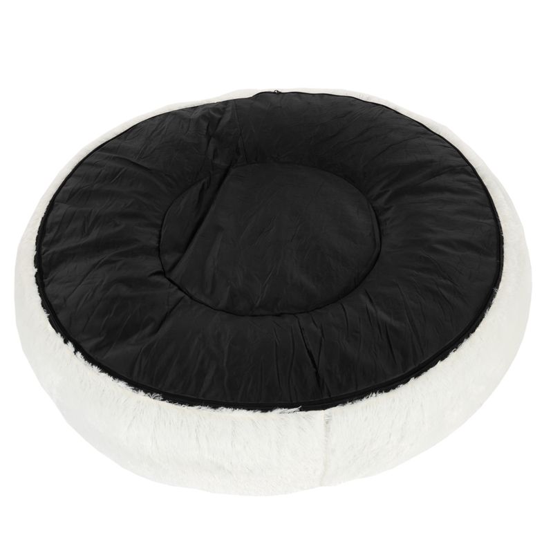 Round, white pet bed with black fabric lying surface. Outer area with soft fur look.