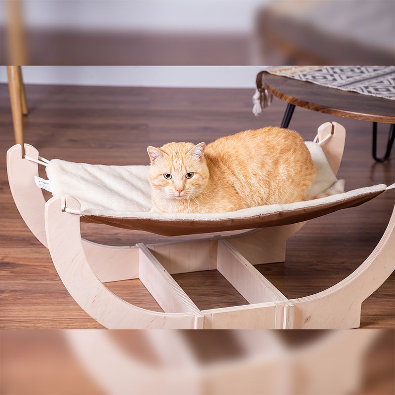 Wooden hammock with beige fabric cover, an orange cat lying on it. Suitable for pets.