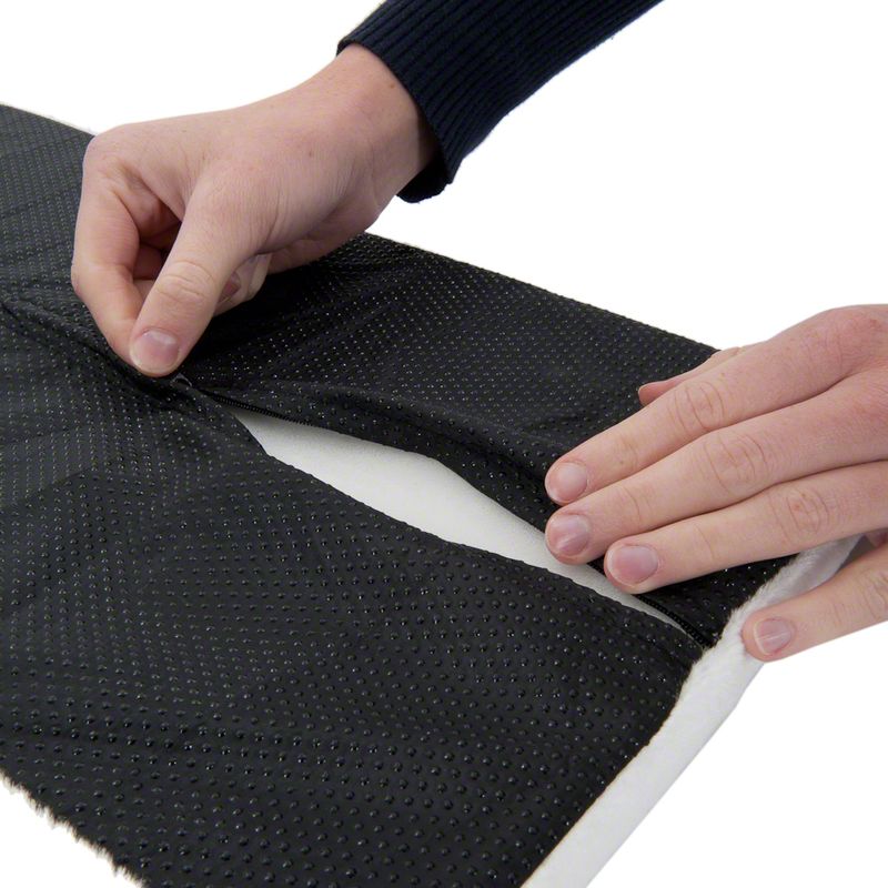 Close-up of hands adjusting a black non-slip mat with dotted texture on white fabric.