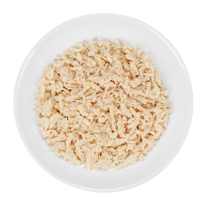 Close-up of shredded, cooked chicken meat on a white plate.
