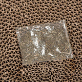 Transparent pouch with dried herbs on a brown, honeycomb-shaped cardboard base.