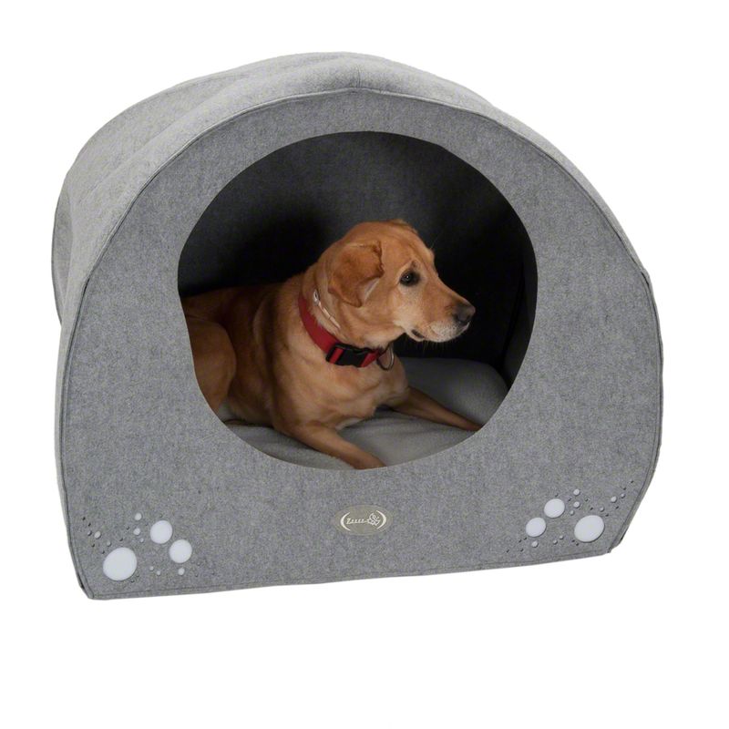 Dog in grey dog cave with paw motif and padded lying surface. Visible logo: Trixie.