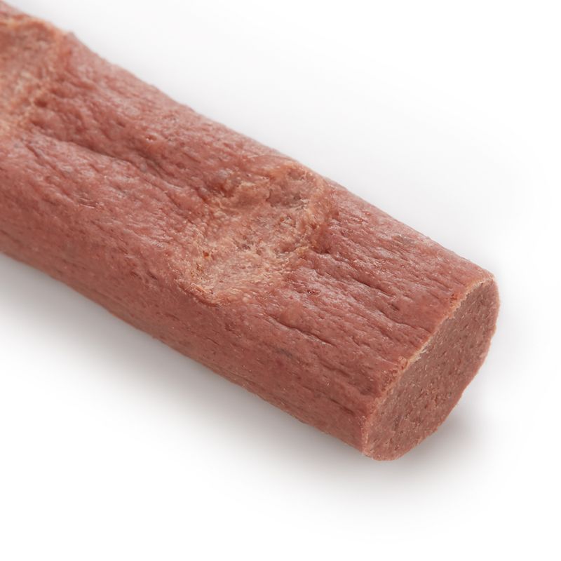 Close-up of a flesh-coloured snack stick with smooth texture and rounded ends.