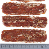 Four elongated dog snacks with brown and white marbling, arranged side by side. Scale at the bottom shows length of approx. 10 cm.